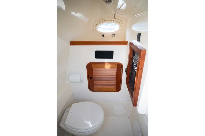 Slide: The Image of Interior of 2014 Hinckley Talaria 29C boat, featuring a compact marine toilet and wooden cabinetry. - 29