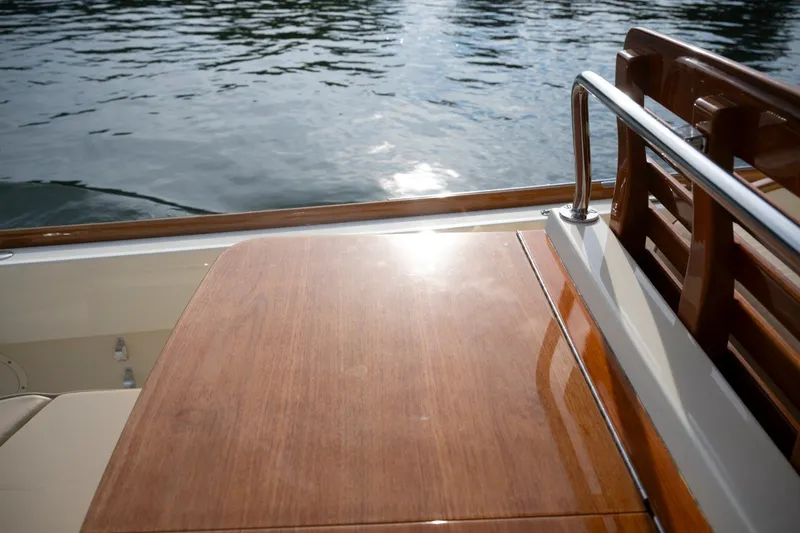 Slide: The Image of 2014 Hinckley Talaria 29C boat with polished wooden deck by the water. - 23
