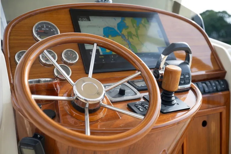 Slide: The Image of Steering wheel and controls of a 2014 Hinckley Talaria 29C boat, featuring a navigation display. - 18