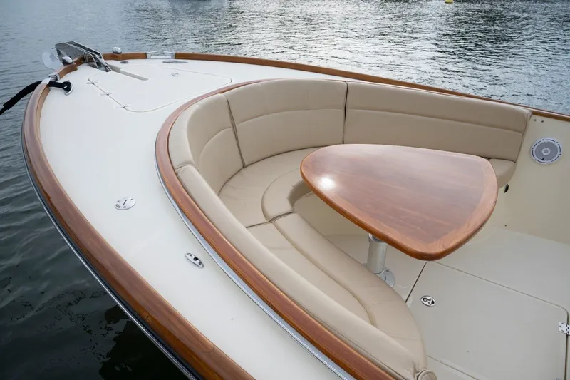 Slide: The Image of 2014 Hinckley Talaria 29C boat with elegant seating and wooden table on calm water. - 11