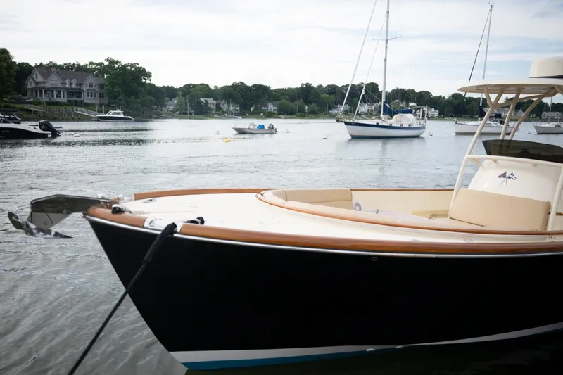 Slide: The Image of 2014 Hinckley Talaria 29C boat docked in a scenic harbor with sailboats. - 10
