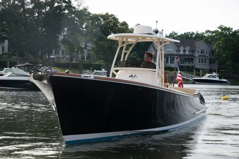 Slide: The Image of 2014 Hinckley Talaria 29C cruising on a serene lake with waterfront homes in the background. - 33
