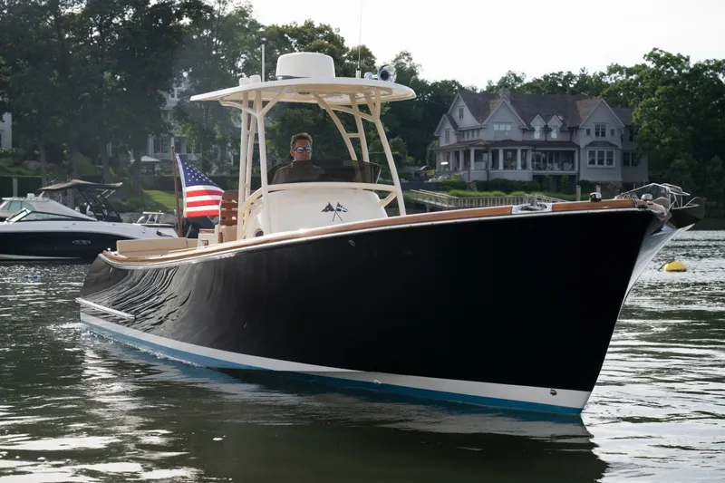 Slide: The Image of A 2014 Hinckley Talaria 29C cruising on calm water, with houses visible in the background. - 5