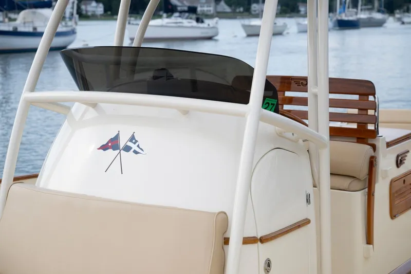 Slide: The Image of 2014 Hinckley Talaria 29C boat with flags, docked in a marina. - 14