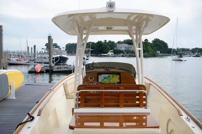 Slide: The Image of 2014 Hinckley Talaria 29C boat docked at marina, featuring elegant wooden helm and navigation system. - 21