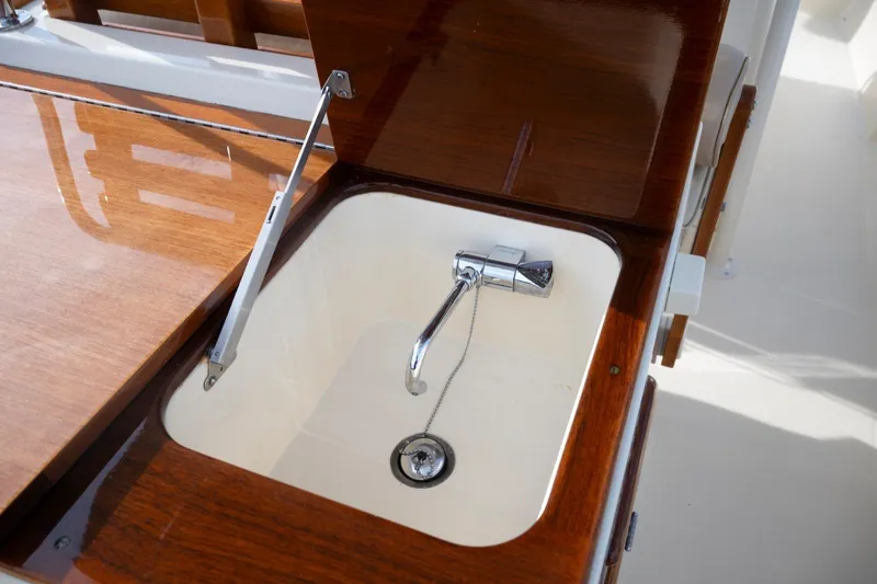 Slide: The Image of 2014 Hinckley Talaria 29C boat sink with wooden cover and chrome faucet. - 24
