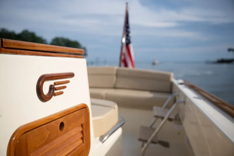 Slide: The Image of 2014 Hinckley Talaria 29C boat with wooden accents and American flag on calm water. - 26