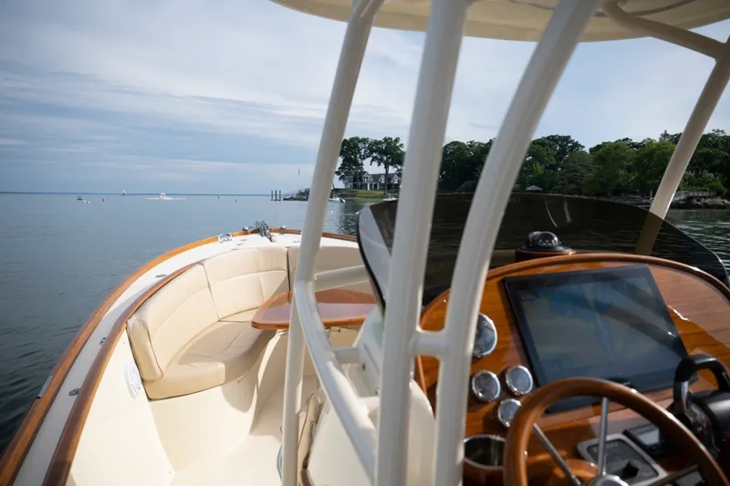 Slide: The Image of 2014 Hinckley Talaria 29C boat interior with helm and seating, cruising on calm waters. - 15