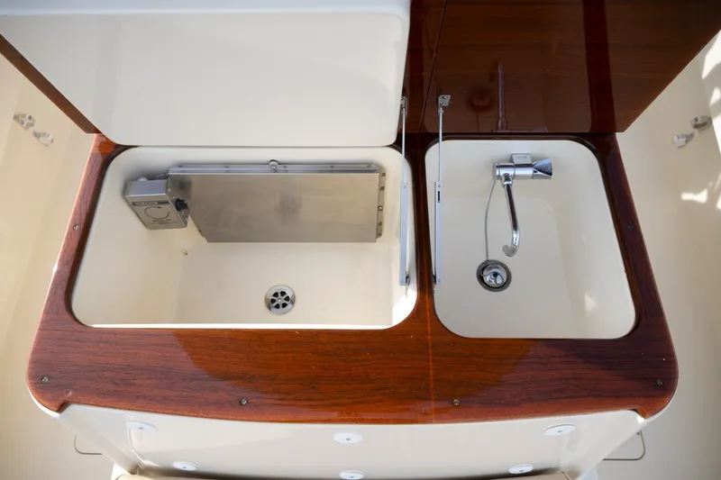 Slide: The Image of 2014 Hinckley Talaria 29C yacht sink and storage area with wooden finish. - 25