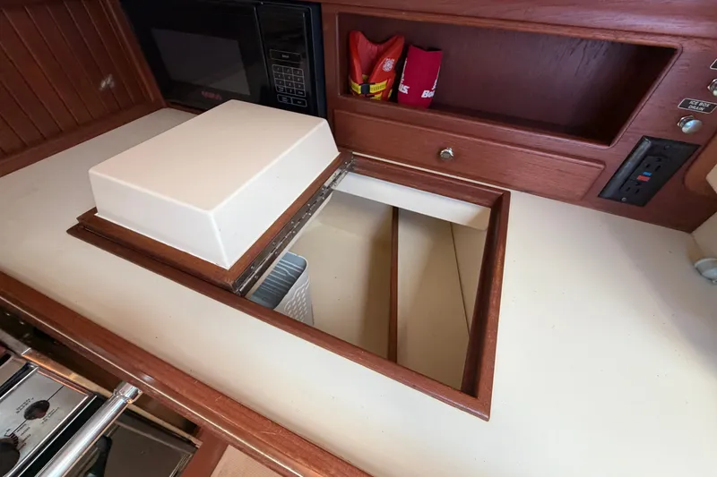 Slide: The Image of Interior of 2000 Island Packet 320 sailboat galley with storage compartment and microwave. - 58