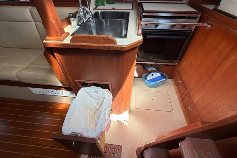 Slide: The Image of Interior of 2000 Island Packet 320 sailboat kitchen with sink, stove, and trash bin. - 60