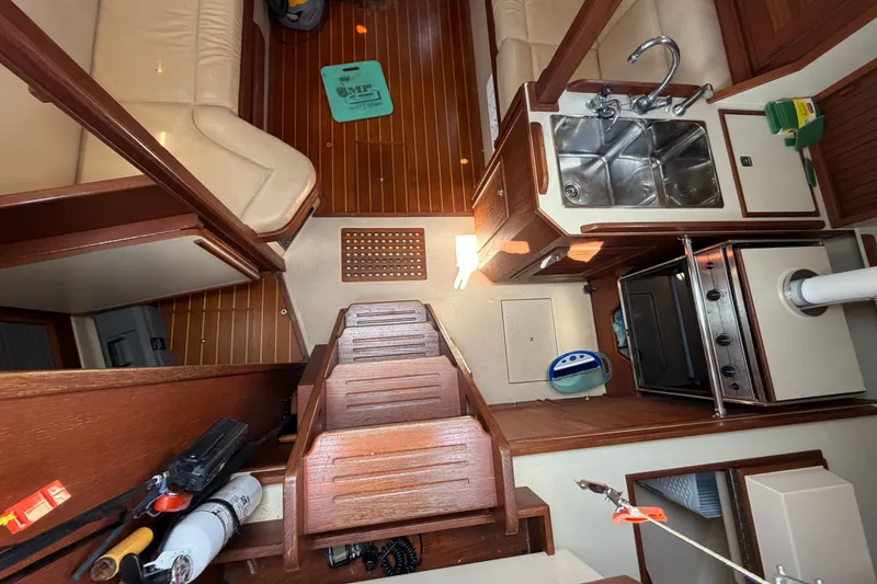 Slide: The Image of Interior of a 2000 Island Packet 320 sailboat, featuring a compact kitchen and seating area. - 51