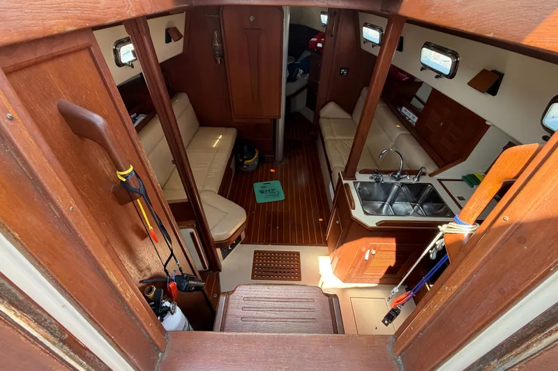 Slide: The Image of Interior of a 2000 Island Packet 320 sailboat, featuring wood finishes and a compact kitchen. - 50