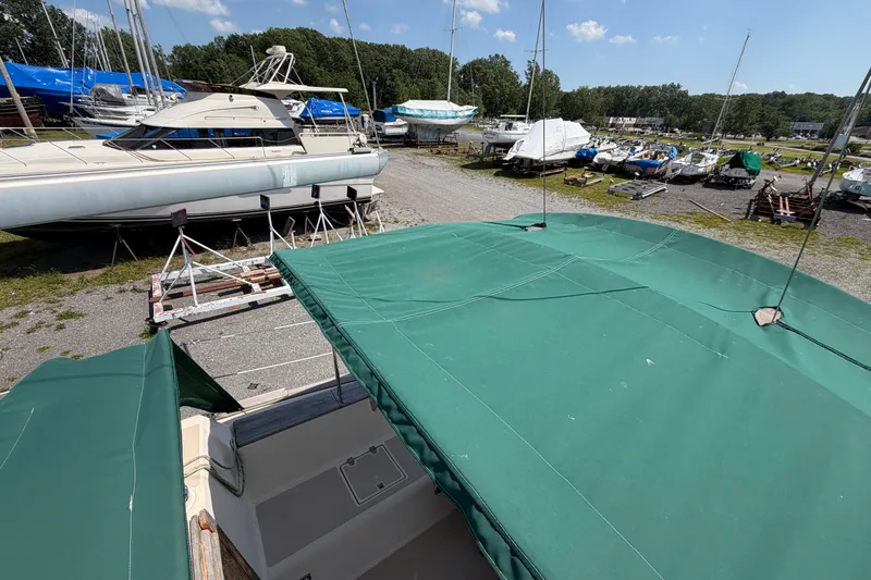 Slide: The Image of 2000 Island Packet 320 sailboat with green canopy in a boatyard, surrounded by other vessels. - 31