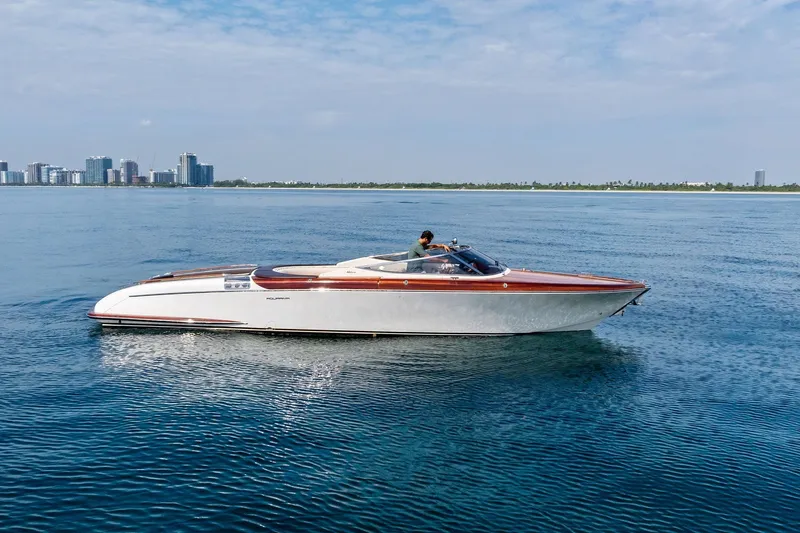 The Image of 2006 Riva 33' Aquariva boat cruising on calm blue waters near a city skyline. - 0
