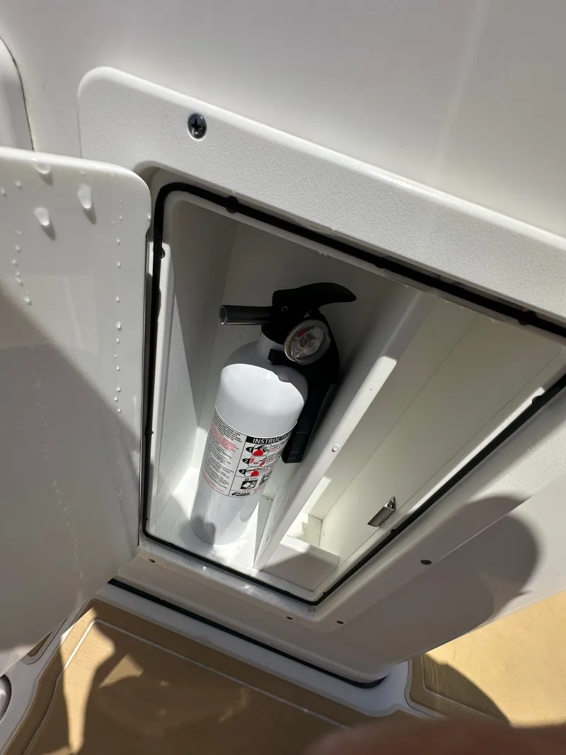 Slide: The Image of A fire extinguisher is mounted in a white storage compartment on a Sportsman Open 282 Center Console boat. - 27