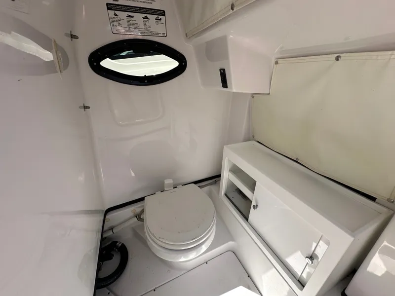 Slide: The Image of The image shows a clean, white boat toilet with a small window and storage space. - 31