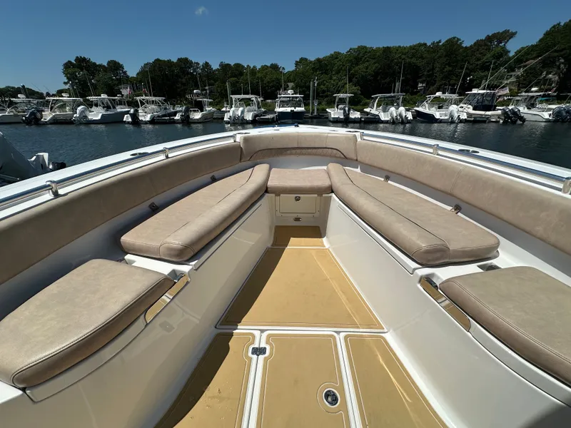 Slide: The Image of The image shows the bow seating area of a 2019 Sportsman Open 282 Center Console boat with beige cushions. - 13