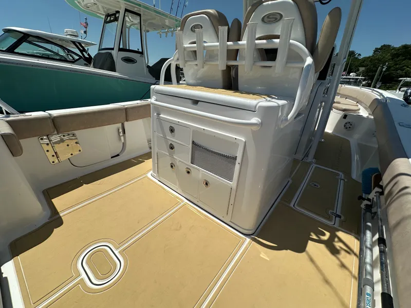 Slide: The Image of The image shows the cockpit of a 2019 Sportsman Open 282 Center Console boat with beige upholstery and storage. - 25