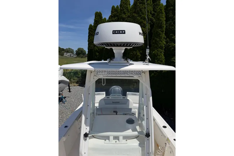Slide: The Image of 2013 Everglades 210 Center Console boat with radar, parked outdoors. - 13