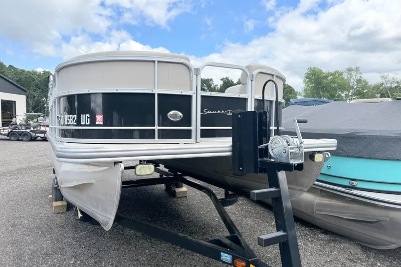 Slide: The Image of 2019 South Bay 520CR pontoon boat on trailer, parked outdoors under a cloudy sky. - 2
