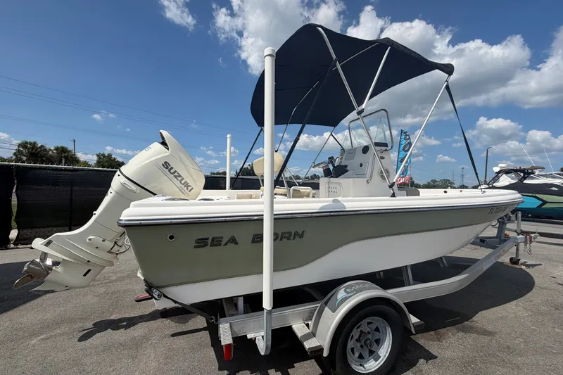 Slide: The Image of 2019 Sea Born SV19 Bay boat with Suzuki outboard motor on trailer, under blue sky. - 2