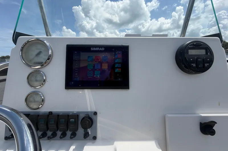 Slide: The Image of 2019 Sea Born SV19 Bay boat dashboard with Simrad display and gauges under a cloudy sky. - 16