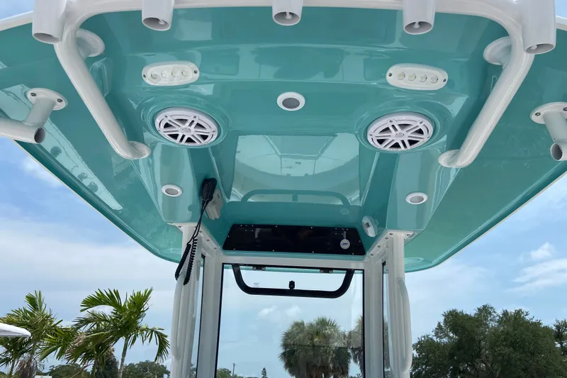 Slide: The Image of 2027 Sportsman Heritage 231 Center Console boat with teal T-top and integrated speakers. - 13