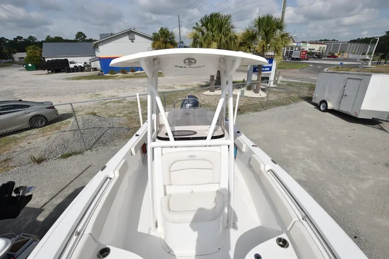 Slide: The Image of 2023 Sea Hunt Ultra 229 boat with T-top, parked outdoors near palm trees. - 11