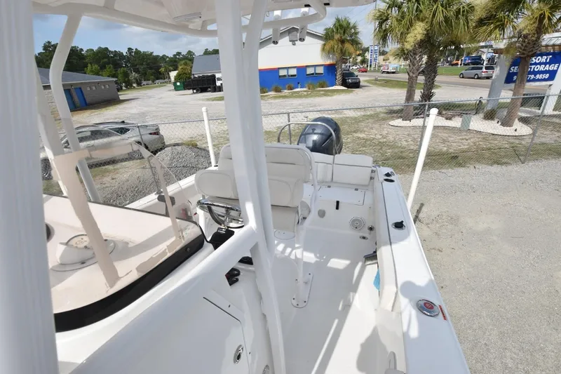 Slide: The Image of 2023 Sea Hunt Ultra 229 boat interior with seating and console, parked near palm trees. - 12