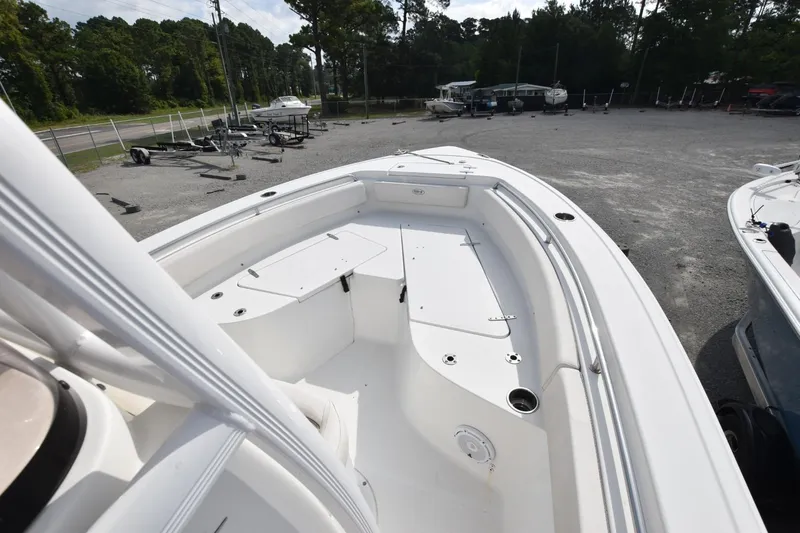 Slide: The Image of 2023 Sea Hunt Ultra 229 boat, spacious deck, parked outdoors, surrounded by trees and trailers. - 10