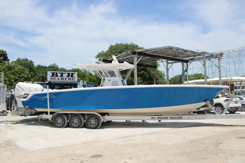 Slide: The Image of 2022 Blackwater 36 Sport boat on trailer at marina, blue hull, clear sky. - 38