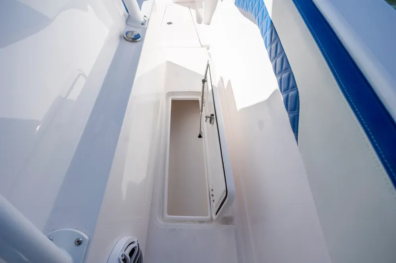 Slide: The Image of Open storage compartment on 2022 Blackwater 36 Sport boat with blue and white interior. - 28