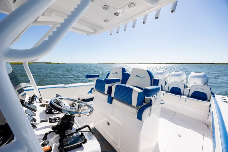 Slide: The Image of 2022 Blackwater 36 Sport boat interior with blue seating, steering wheel, and ocean view. - 14