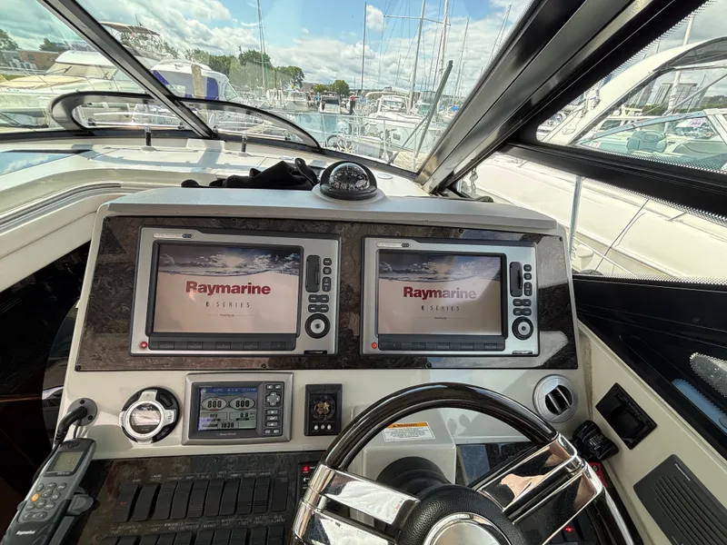 Slide: The Image of The cockpit of the 2012 Sea Ray 470 Sundancer features two Raymarine screens and a steering wheel. - 12