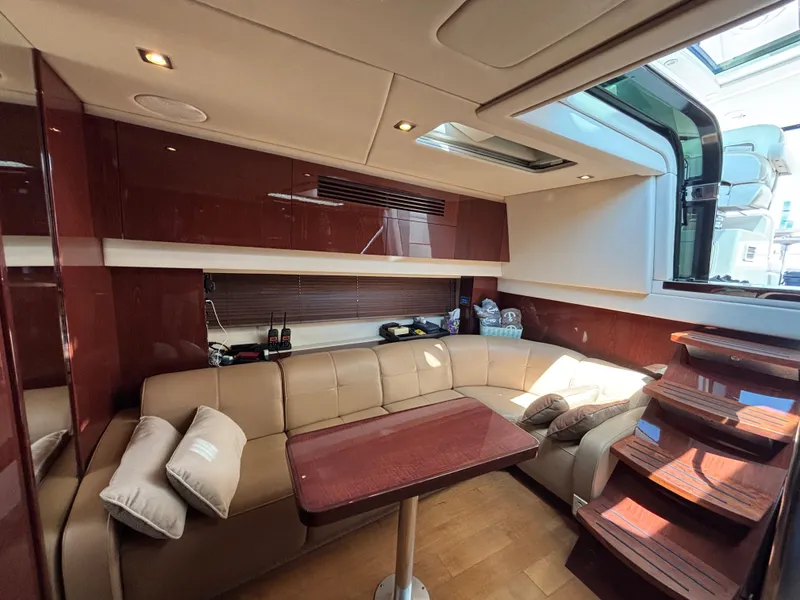 Slide: The Image of The interior of a 2012 Sea Ray 470 Sundancer features an elegant seating area with a wooden table and stairs. - 16