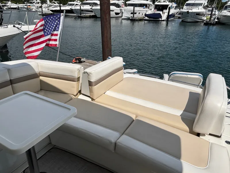 Slide: The Image of The 2012 Sea Ray 470 Sundancer features a comfortable seating area with a table and an American flag in the background. - 6