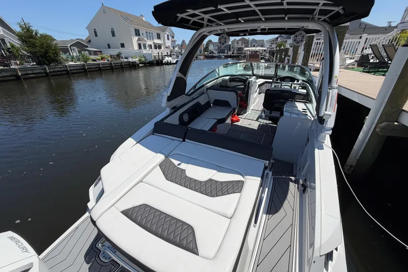 Slide: The Image of 2023 Monterey 305SS Super Sport boat docked in a scenic waterfront area. - 13