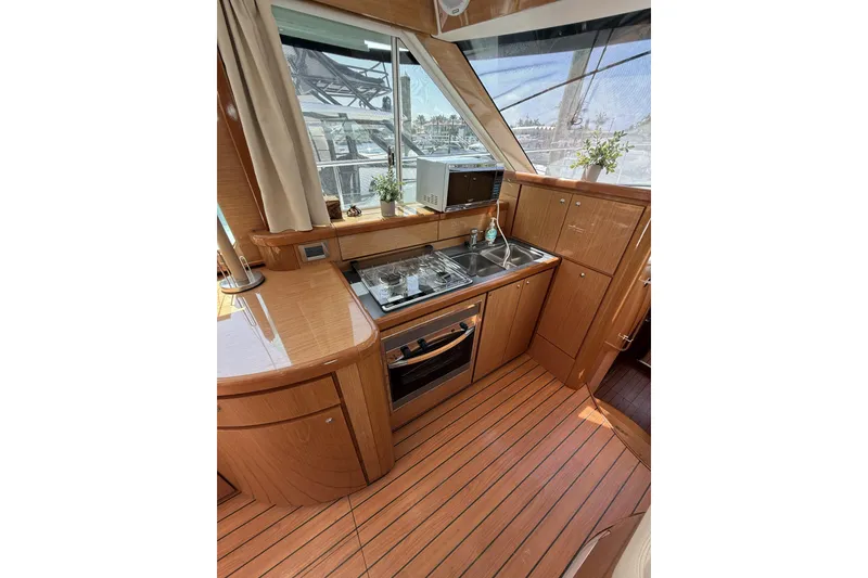 Slide: The Image of Luxurious 2008 Beneteau Antares 13.80 yacht kitchen with wood finish and modern appliances. - 14