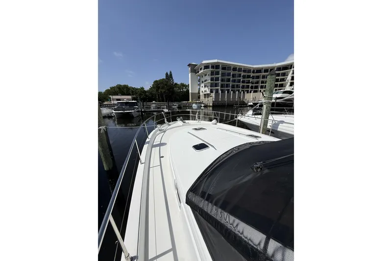 Slide: The Image of 2008 Beneteau Antares 13.80 yacht docked at marina with modern building backdrop. - 5