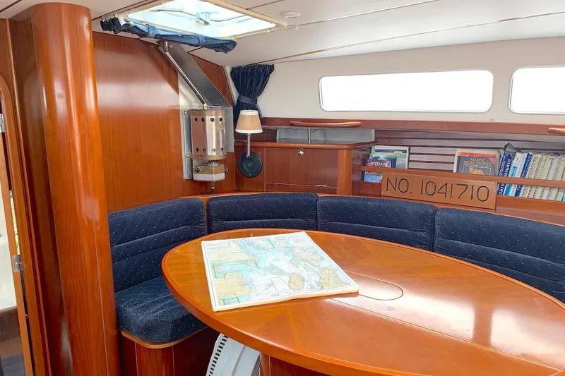 Slide: The Image of Interior of 1990 Beneteau Oceanis 390 yacht with wooden dining area and nautical map. - 6