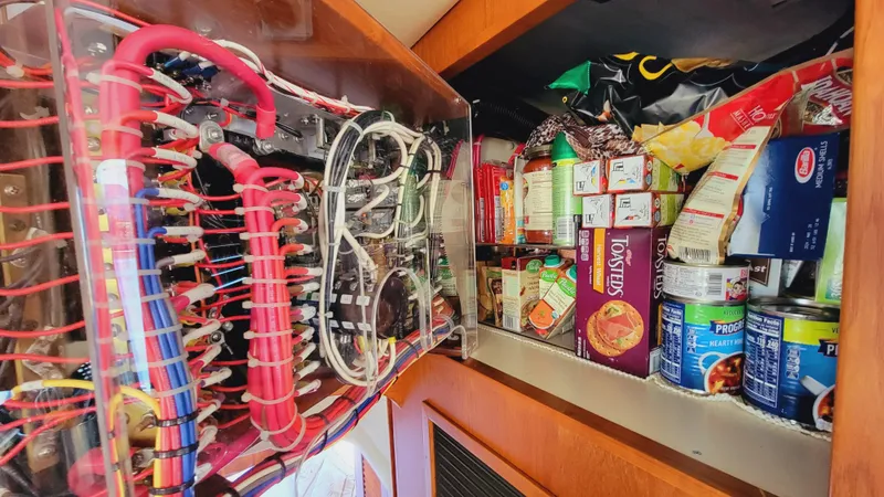 Slide: The Image of A cabinet inside a boat shows electrical wiring and stored food items. - 25