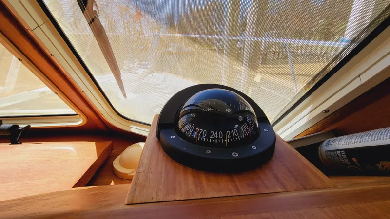 Slide: The Image of A compass is mounted on a wooden dashboard in a boat, overlooking the water. - 48