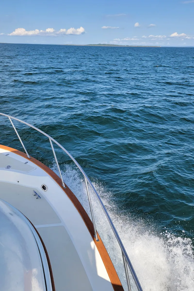 Slide: The Image of A boat with wooden trim navigates calm, blue waters under a clear sky. - 44