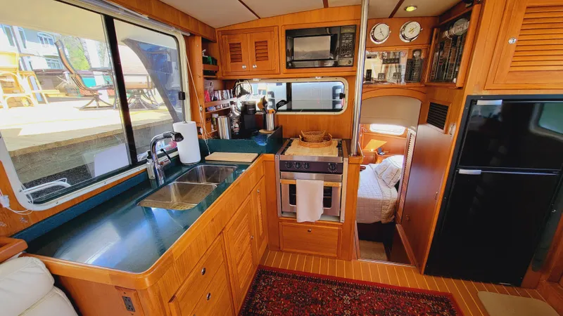 Slide: The Image of The galley of a 2003 Pacific Seacraft 38T Fast Trawler with wooden cabinets and modern appliances. - 7