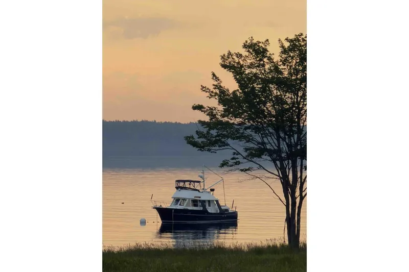 Slide: The Image of Pacific Seacraft 38T Fast Trawler, 2003, anchored at sunset near a tree-lined shore. - 160