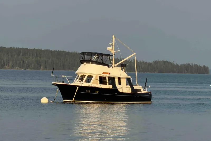 Slide: The Image of 2003 Pacific Seacraft 38T Fast Trawler anchored on calm water with forested background. - 99