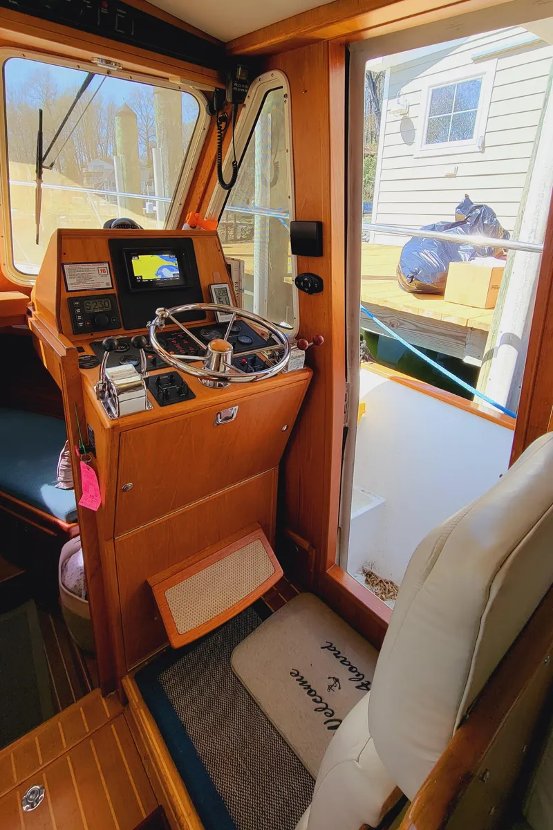 Slide: The Image of The cockpit of a 2003 Pacific Seacraft 38T Fast Trawler with wood paneling and a steering console. - 15