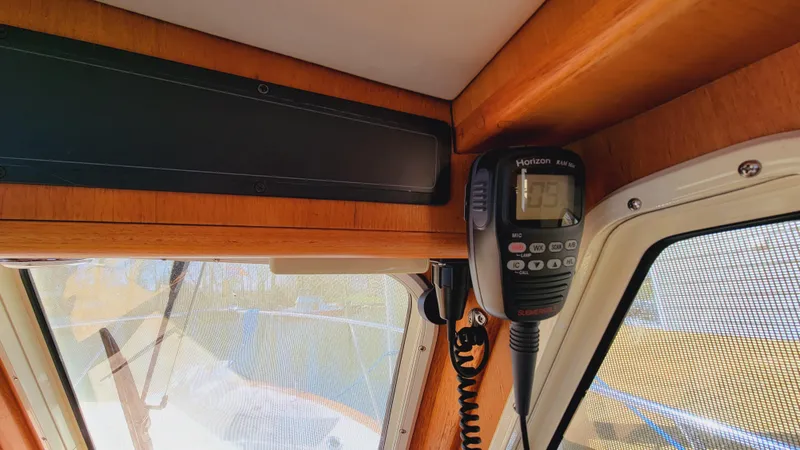 Slide: The Image of A radio is mounted in the corner of a boat, surrounded by wood paneling and windows. - 47