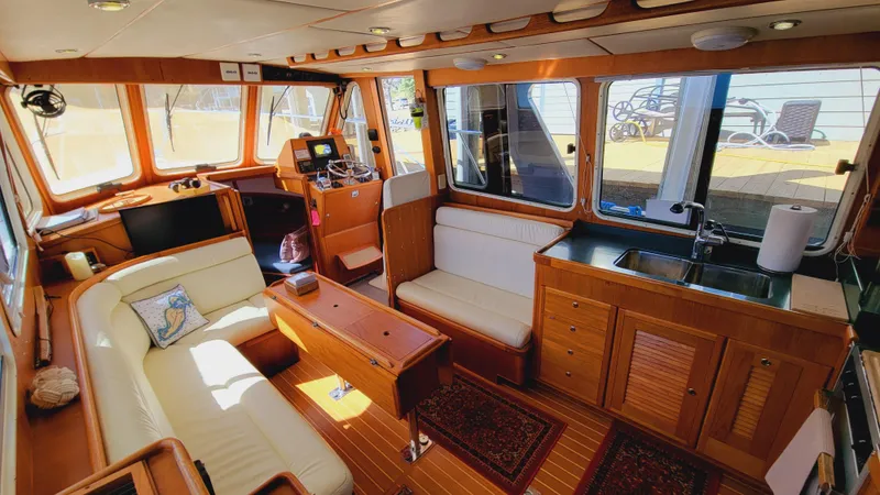 Slide: The Image of The interior of a 2003 Pacific Seacraft 38T Fast Trawler features a cozy seating area, wooden furnishings, and large windows. - 16